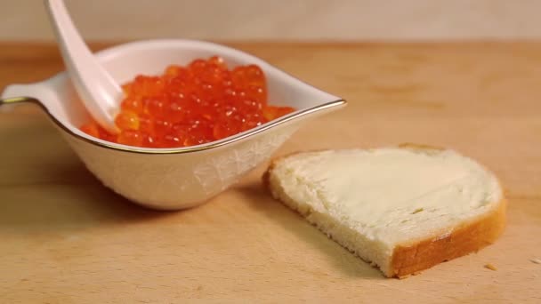 Una mano femminile stende un panino al caviale con caviale rosso . — Video Stock