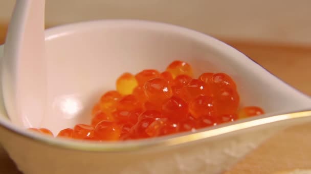 A female hand spreads a caviar sandwich with red caviar. — Stock Video