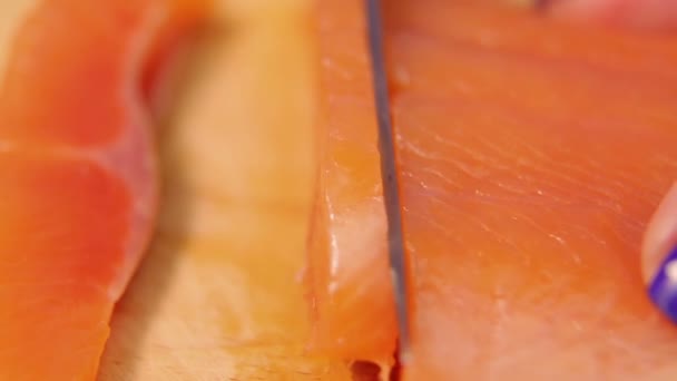 Female hand cuts trout fish for sandwiches on a wooden board. — Stockvideo