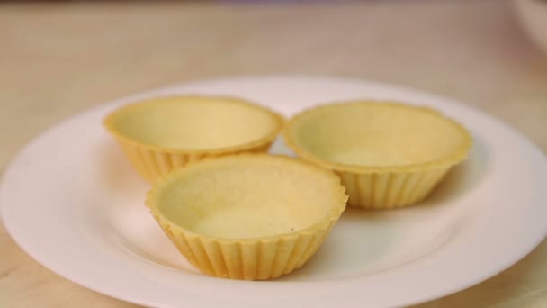 A female hand puts a spoonful of salad mass into tartlets on a white plate. — Stock Video