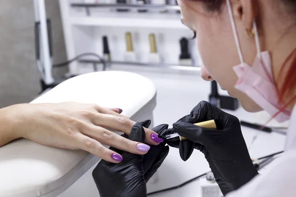 Una manicure applica un rivestimento opaco con un pennello sulle unghie dei clienti primo piano . — Foto Stock