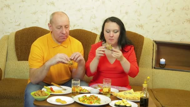 Muži a ženy rodina jíst smažené kuře a pít pivo ve večerních hodinách u večeře — Stock video