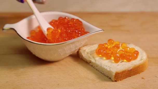 Una mano femenina extiende un sándwich de caviar con caviar rojo — Vídeos de Stock
