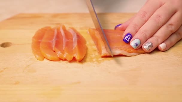 Female hand cuts red trout fish for sandwiches on a wooden board — Stock Footage Female hand cuts red trout fish for sandwiches on a wooden board Royalty Free Stock Footage
