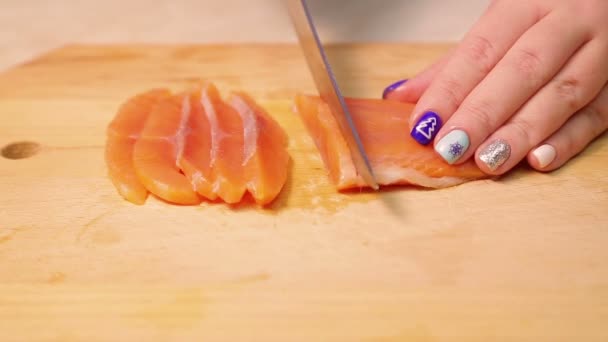 Vrouwelijke hand snijdt rode forel vis voor sandwiches op een houten plank — Stockvideo