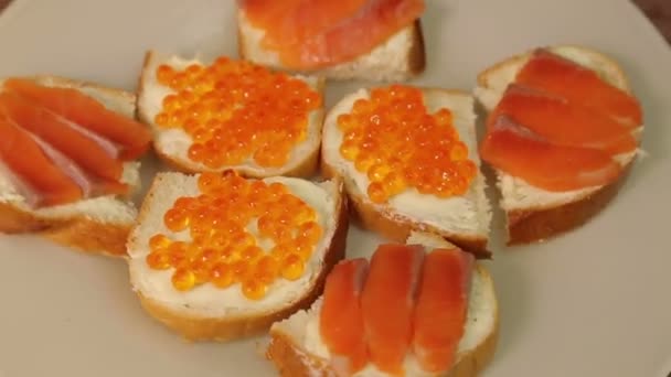 Тарелка с бутербродами с красной рыбой и красной икрой вращается по кругу — стоковое видео
