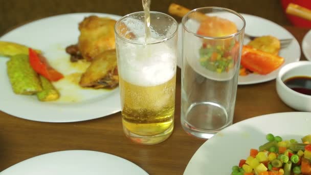 Foamy light beer from a bottle is poured into a transparent glass — Stock Video