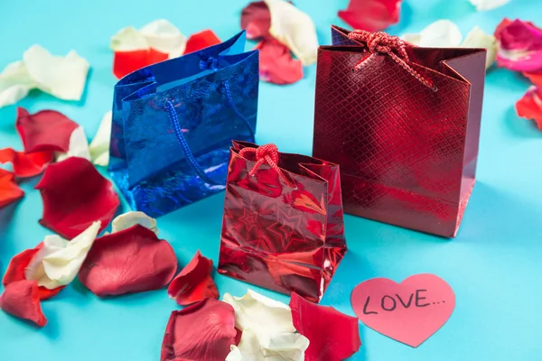 Valentines hari tas hadiah pada latar belakang biru dalam kelopak mawar . — Stok Foto