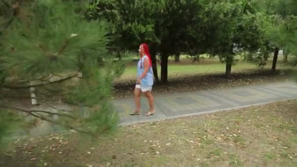Une femme dans un parc marchant le long d'une allée verte — Video
