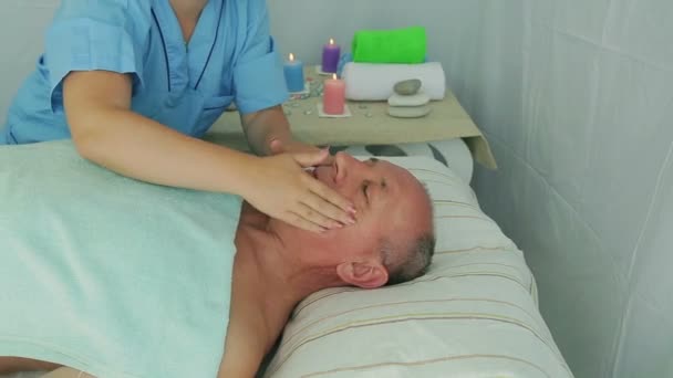 Ženská beautik dodává klientovi v lázeňském salonu v lázních masáž obličeje — Stock video