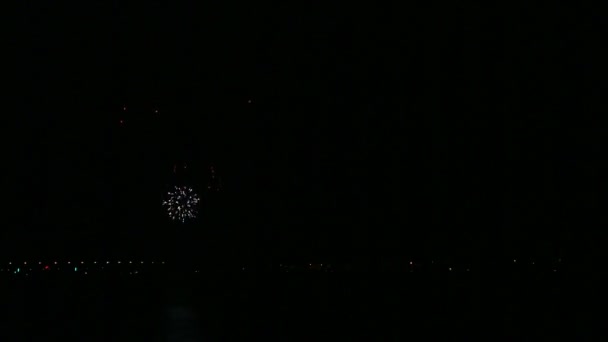 Fuegos artificiales festivos de color brillante en el cielo nocturno sobre el río que se refleja en el agua — Vídeos de Stock