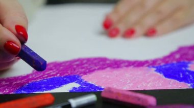 Female hand draws evening sky on white blue pastel paper