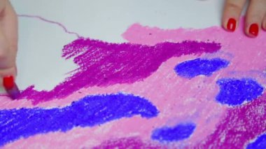 Kadın eli, gün batımında mor pastel gökyüzü ile beyaz kağıda çizer.