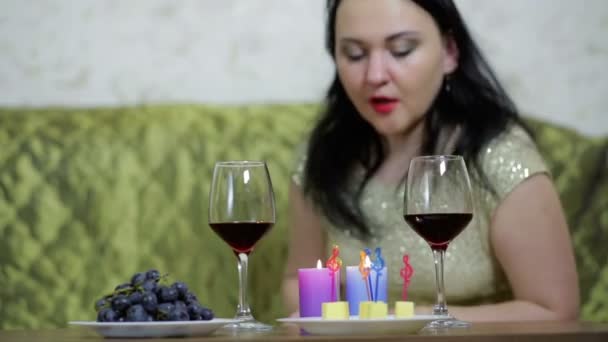Женщина в слезах задувает свечи и пьет красное вино . — стоковое видео