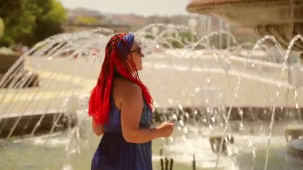 穿着蓝色衣服的快乐的女人在公园的喷泉边跳舞 — 图库视频影像