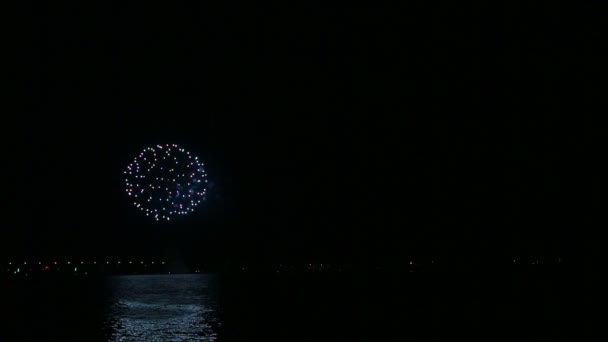 Brillantes fuegos artificiales festivos en el cielo nocturno sobre el río con reflejo en el agua — Vídeos de Stock