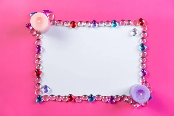 Dia dos Namorados moldura em um fundo rosa feito de seixos na forma de um coração com espaço em branco e velas nos cantos . — Fotografia de Stock