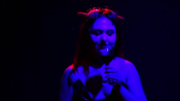 Жіночий диявол з огидною посмішкою на обличчі п'є кров з келиха, як вино — стокове відео
