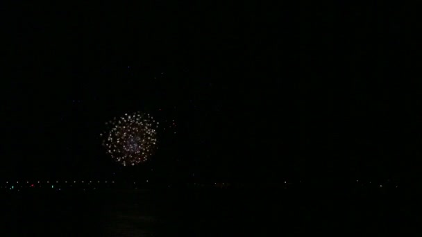 Яркий сверкающий праздничный фейерверк в ночном небе над рекой, отражающийся в воде — стоковое видео