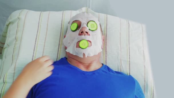 Uma esteticista feminina remove uma máscara facial hidratante de um cliente em um salão de spa . — Vídeo de Stock