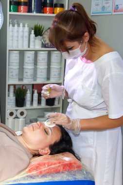 Kozmetik uzmanı müşterinin kaşlarını karıştırma yöntemiyle düzeltir.