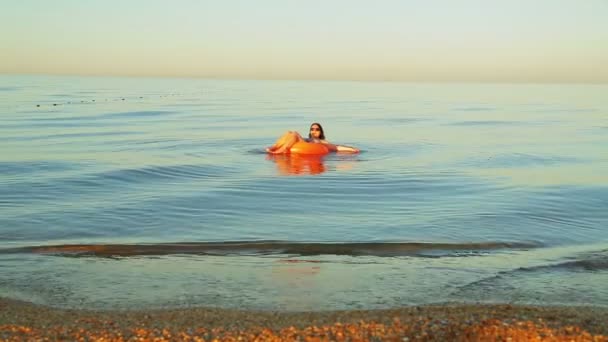Μελαχρινή γυναίκα με μαγιό σε έναν κύκλο κολύμβησης στη θάλασσα κοντά στην ακτή — Αρχείο Βίντεο