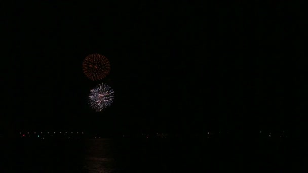 Яркий сверкающий праздничный фейерверк в ночном небе над рекой, отражающийся в воде . — стоковое видео