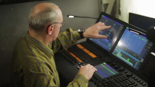 Um programador de iluminação masculino em um controle remoto programa a luz do palco para um show — Vídeo de Stock