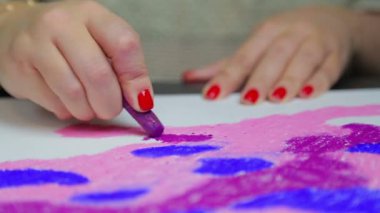 Kadın eli, gün batımında mor pastel gökyüzü ile beyaz kağıda çizer..