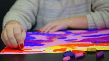 Kadın eli gün batımında beyaz kağıda sarı bir pastel bulut çizer.