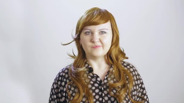 A young woman on a white background shows an emotion of anger — Wideo stockowe