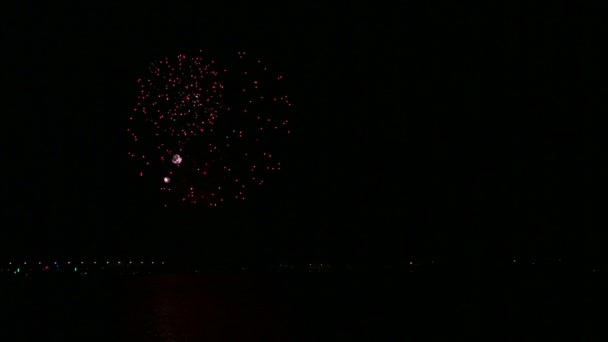 Яркий светящийся праздничный фейерверк в ночном небе над рекой, отражающийся в воде . — стоковое видео