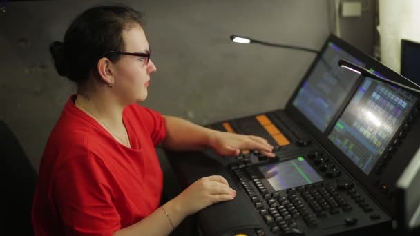 A female programmer illuminator at the remote control programs the stage light for the show — Stockvideo