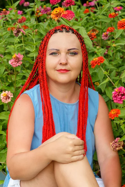 Молодая женщина с рыжими волосами позирует в красно-оранжевых цветах . — стоковое фото