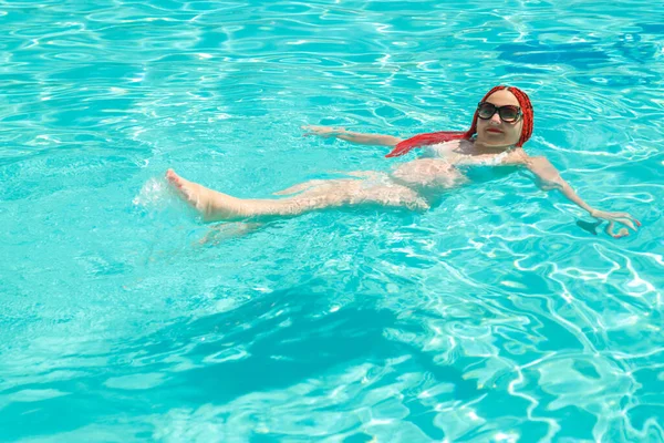 Una mujer con coletas africanas nada sobre su espalda en la piscina . —  Fotos de Stock