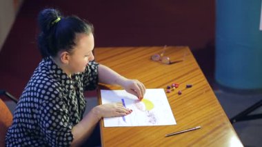 Genç bir sanatçı pastel tekniği kullanarak bir manzara üzerinde çalışıyor..