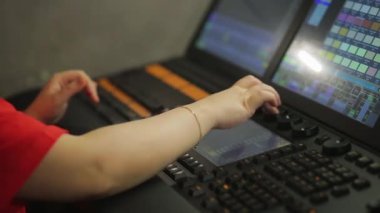Uzaktan kumandada çalışan bir kadın sahne ışığını programlıyor.