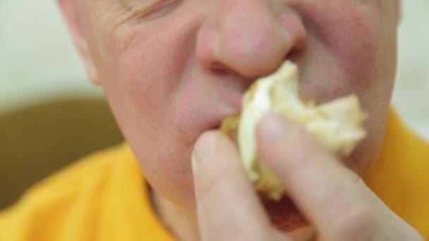 Um homem com apetite come um hambúrguer ao jantar . — Vídeo de Stock