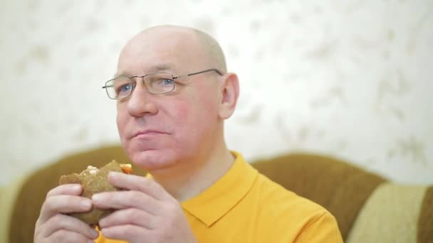 Un uomo con l'appetito mangia un hamburger a cena — Video Stock