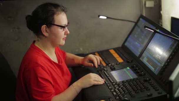 Um iluminador feminino no controle remoto programa a luz do palco para o show — Vídeo de Stock