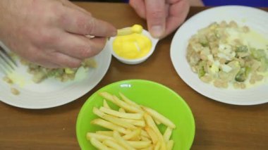 Salata ve patates kızartmalı bir masa. Erkek ve kadın elleri ürünleri alır..