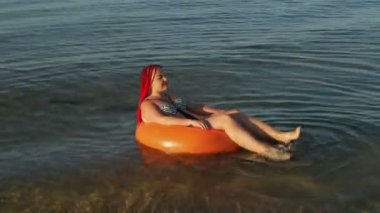 Yüzme havuzunda deniz dalgaları üzerinde mayo giymiş kızıl saçlı bir kadın...