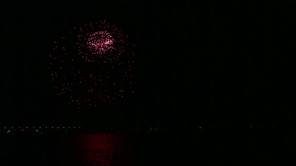 Λαμπερά εορταστικά πυροτεχνήματα στο νυχτερινό ουρανό πάνω από το ποτάμι αντανακλώντας στο νερό. — Αρχείο Βίντεο