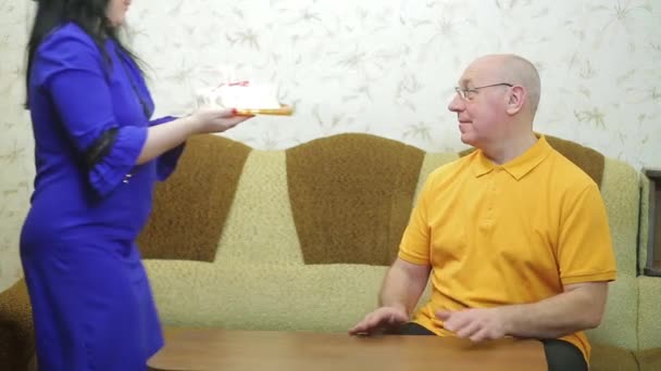 Die Frau schenkt ihrem Mann eine Torte, er macht einen Wunsch und bläst die Kerzen aus — Stockvideo