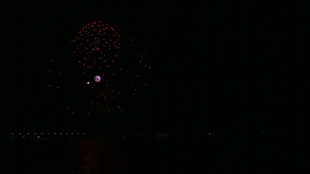 Fiery festive fireworks in the night sky above the river reflecting in the water — Stock Video