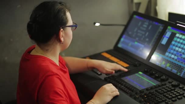 A woman lighting director at the console programs the stage light for the show — Stockvideo