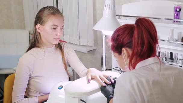 Маникюрша в салоне красоты украшает ногти клиентов гелевым лаком со стразами — стоковое видео