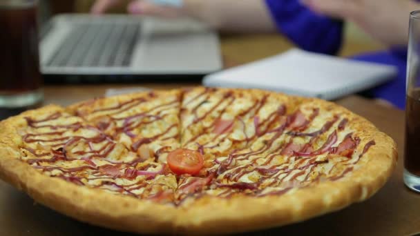 Pizza em uma placa na mesa e mãos de mulheres digitando em um teclado de computador no fundo. Mudança de foco — Vídeo de Stock