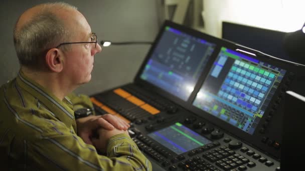 Um programador de iluminação masculino em um controle remoto programa a luz do palco para um show — Vídeo de Stock