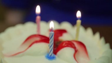 A person blows out burning candles on a holiday cake.